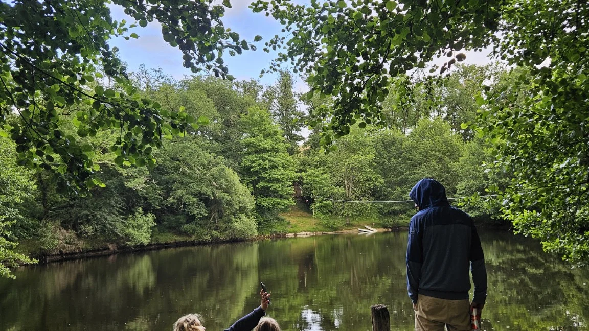 Drei Menschen auf einem Steg am See, von hinten aufgenommen