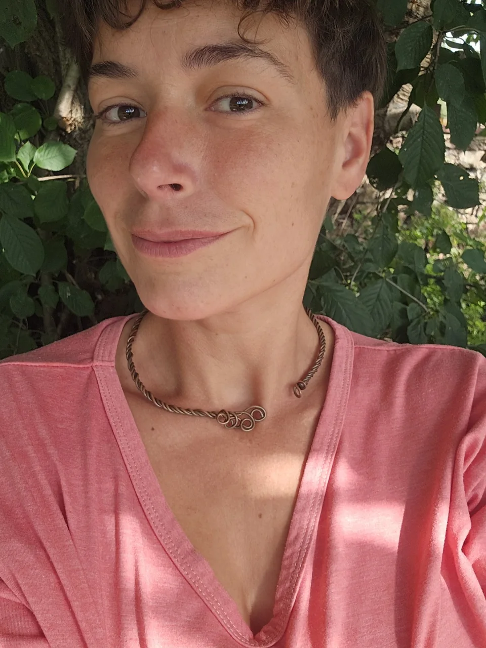 Karo mit kurzen Haaren im roten T-Shirt, draußen im Grünen